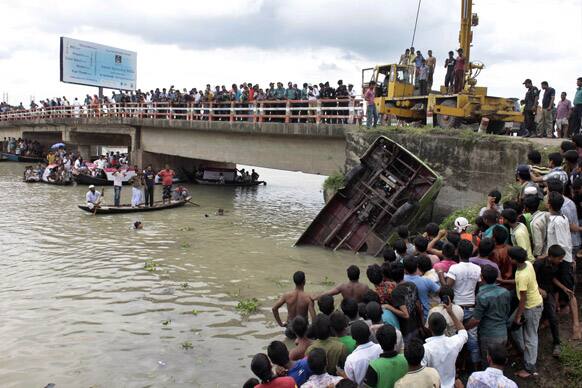 Bangladeshi people watch as rescue workers pull out a bus that plunged into the river Turag in Ashulia, near Dhaka, Bangladesh.