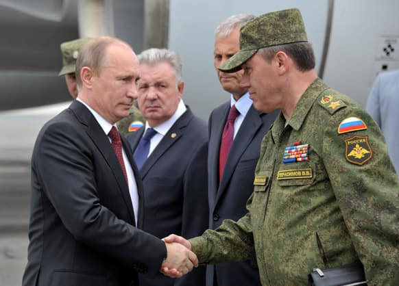 Russian President Vladimir Putin, shakes hands with chief of Russia`s military`s General Staff Valery Gerasimov, at an airport of Yuzhno-Sakhalinsk, on Sakhalin Island.
