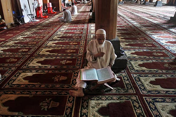 An elderly Kashmiri Muslim man reads verses from the Quran, Islam`s holy book inside the Jamia Masjid, or Grand Mosque in Srinagar.