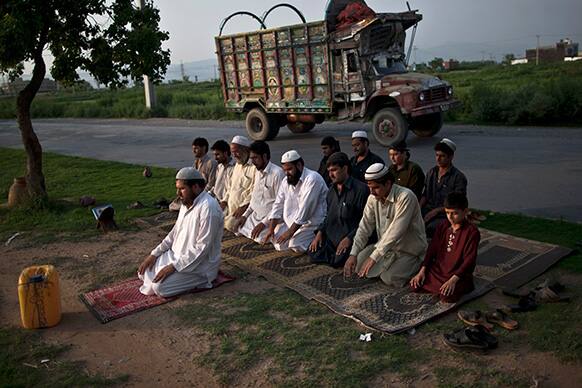Pakistani workers attend the daily Asr prayer, or afternoon prayer, on a street median during the Muslim holy fasting month of Ramadan, on the outskirts of Islamabad.