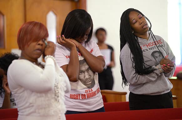 Tammy Haynes, left, Whitney Tillman, center, and Crystal Haynes react during a sermon at a youth service at the St. Paul Missionary Baptist Church in Sanford, Fla.