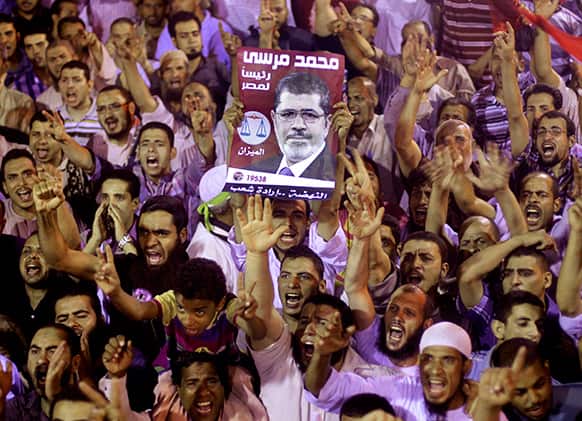 Supporters of Egypt`s ousted President Mohammed Morsi chant slogans as they hold his poster, in a park near Cairo University, where protesters have been camping out in Giza, Cairo, Egypt.