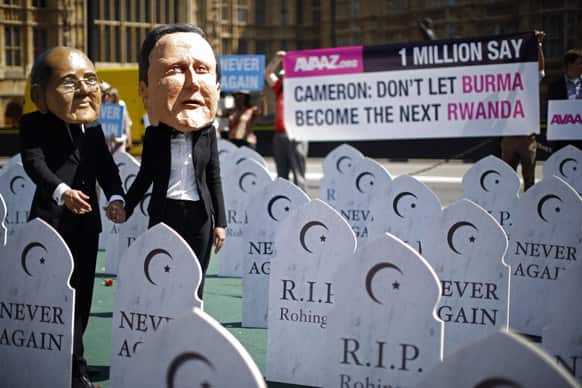 Campaigners supporting the `Avaaz, Burma Campaign UK` organization wear masks representing British Prime Minister David Cameron, right, and Myanmar`s President Thein Sein as they pose for photographs during a protest photocall outside the Houses of Parliament in London.