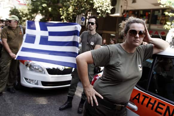 Striking Municipal police officers hold a Greek flag during a protest against new austerity cuts that will affect thousands of public sector workers, outside the Greek Parliament in Athens.