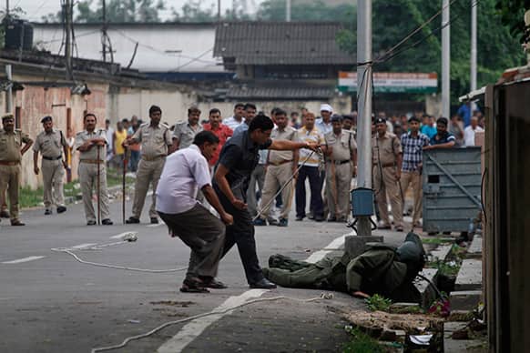 Indian policemen and civilians watch as bomb disposal squad members inspect a suspicious object found lying in a drain following bomb scare that turned out to be hoax in Allahabad.