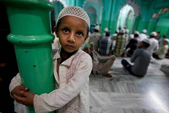 A young Indian Muslim boy looks on as others pray after breaking their Ramadan fast at a Mosque in Allahabad.