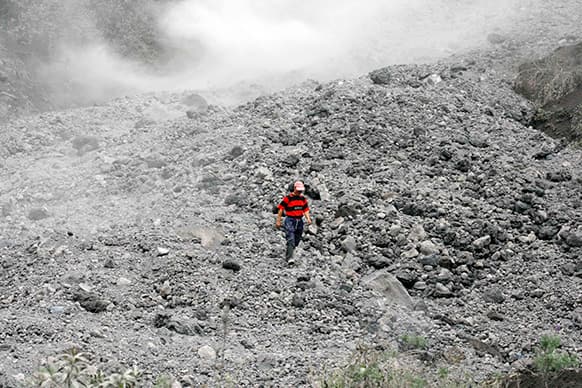 A man walks on rocks and ashes spewed by the Tungurahua volcano in the outskirts of the village of Cusua, Tungurahua province, Ecuador.