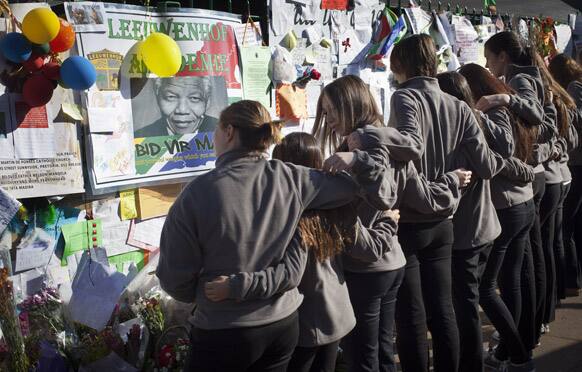 Toronto Children`s Chorus choral group, who are on a tour taking part in the Ihlombe South African Choral Festival, hug each other as they observe some of the get-well messages and flowers, after singing outside the Mediclinic Heart Hospital where Nelson Mandela is being treated in Pretoria.
