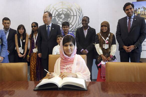 Malala Yousafzai signs United Nations Secretary-General Ban Ki-moon`s guest books as Ban Ki-moon and youth delegates, at United Nations headquarters.