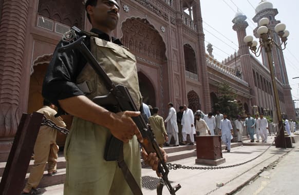 A Pakistani police officer stands guard as people proceed to offer Friday prayers at a local mosque in Peshawar, Pakistan. Muslims throughout the world are celebrating the holy fasting month of Ramadan when observants fast from dawn till dusk.