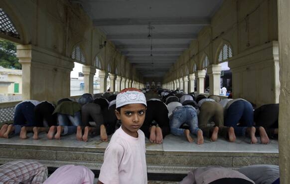 A Muslim boy walks past elders offering Friday prayers at Mecca Masjid mosque in Hyderabad. Muslims throughout the world are celebrating the holy fasting month of Ramadan, refraining from eating, drinking, and smoking from dawn to dusk.
