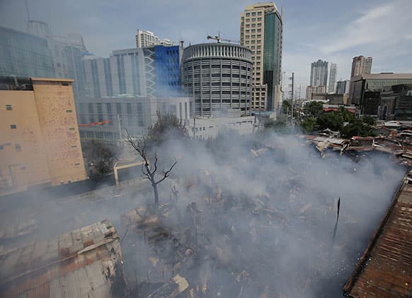 Smoke billows out from a slum colony at the financial district of Makati, south of Manila, Philippines.
