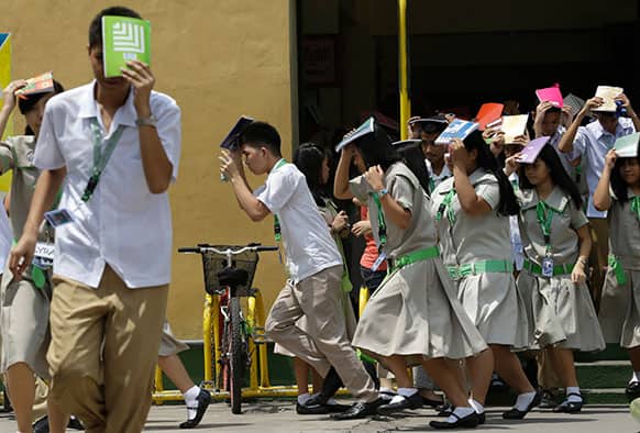 Students of Sta. Elena High School cover their heads with their notebooks as they rush out of their campus to simulate an earthquake during a drill to coincide with the ongoing Asian Crisis Management Conference at Marikina city east of Manila, Philippines.