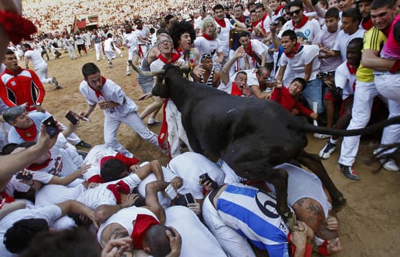 A cow jumps over revelers lying down on the bull ring as one of them is pushed by the animal at the end of the fifth run of the famed San Fermin festival, in Pamplona northern Spain.