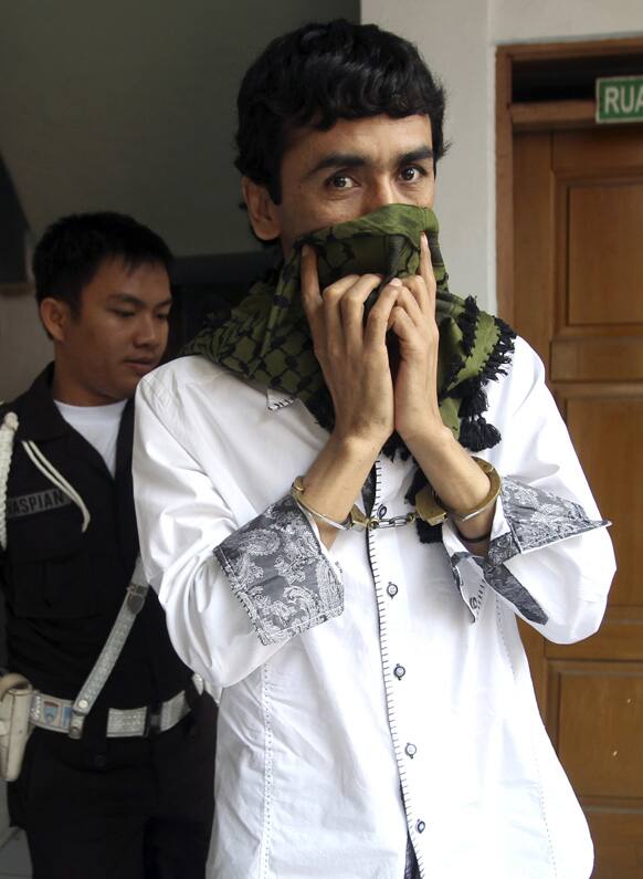 Alleged people smuggler Sayed Abbas is escorted by a security guard upon arrival for his extradition hearing at a district court in Jakarta, Indonesia.