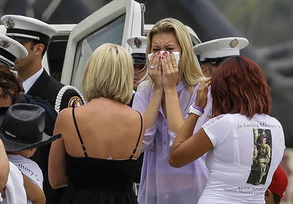 Mourners of fallen firefighter, Kevin Woyjeck, grieve at the coffin carrying his remains after arriving aboard a C-130 transport plane at the Los Alamitos Army Airfield at the Joint Forces Training Base in Los Alamitos, Calif.