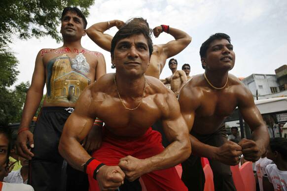 Men flex their muscles as they participate in the annual chariot procession of Hindu god Lord Jagannath in Ahmadabad.