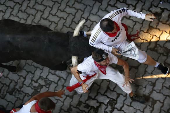 Revelers are chased by a Victoriano del Rio ranch fighting bull during the running of the bulls of the San Fermin festival, in Pamplona, Spain.