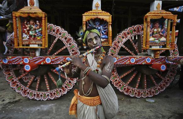 A devotee dressed as Lord Krishna plays the flute ahead of the annual Rath Yatra or Chariot procession of Lord Jagannath in Puri, 60 kilometers (37 miles) from the eastern Indian city of Bhubaneswar.
