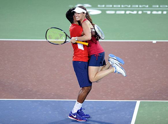 Washington Kastles` Leander Paes, left, of India, picks up and celebrates with Martina Hingis, right, of Switzerland, after they won a World Team Tennis mixed doubles match against the Boston Lobsters, in Washington.