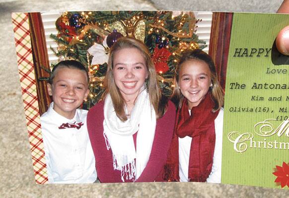 A neighbor holds a 2012 Christmas card showing Mills Antonakos, left, Olivia Antonakos, center, and Anastacia Antonakos, in Greenville, S.C.