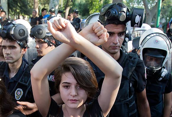 A woman holds her arms crossed as riot police pushes people out of Gezi park in Istanbul, Turkey.