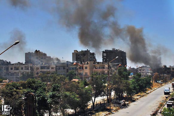 Citizen journalism image provided by Lens Young Homsi, which has been authenticated based on its contents and other AP reporting, black smoke rises from buildings damaged by Syrian government airstrikes and shelling in Homs, Syria.