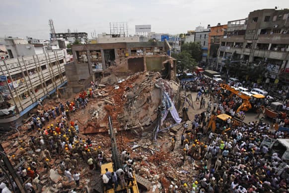 Indians watch as Indian Fire officials and rescue workers look for survivors at the site of a collapsed building, in Hyderabad.