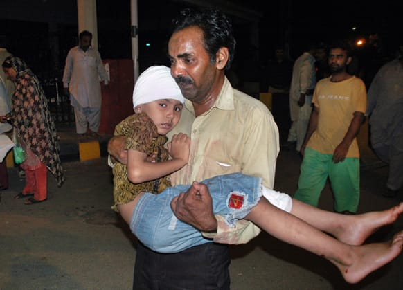 A Pakistani carries his son who was injured in a bomb blast after the boy receives initial treatment at a local hospital in Lahore, Pakistan.