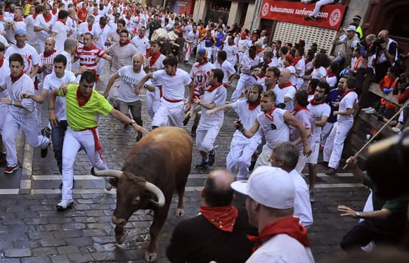 Revelers go after a Alcurrucen ranch fighting bull on the Estafeta corner during the first running of the bulls at the San Fermin fiestas, in Pamplona northern Spain.