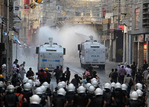 Police uses water cannons against protesters as media and riot policemen run behind the trucks in Istiklal Street, Istanbul`s main shopping strip, during clashes.