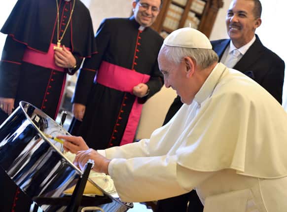 Pope Francis tries out a steelpan, the traditional percussion instrument of Trinidad and Tobago presented by President Anthony Carmona during their private audience at the Vatican.
