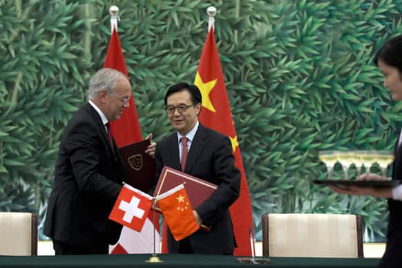 Chinese Commerce Minister Gao Hucheng, center, and Swiss Federal Counsellor Johann Schneider-Ammann shake hands after they signed a free-trade agreement at China`s Ministry of Commerce in Beijing.
