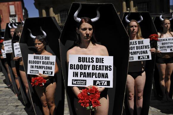 Anti-bullfighting demonstrators protest against the bulls runs, while standing in cardboard coffins and holding red flowers, on the Ayuntamiento Square in Pamplona northern Spain.