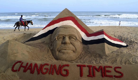 A man rides a horse past a sand sculpture of former ousted Egyptian President Mohammed Morsi created by sand artist Sudarshan Pattnaik on a beach in Puri.