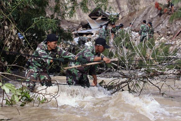 Indonesian soldiers use a rope to cross a swollen river as they search for victims of a landslide triggered by Tuesday`s earthquake in Serempah, Aceh province.