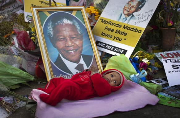 Oamohetswe Mabitsela, 4 months old, is placed by his mother next to a picture of Nelson Mandela for her to take a photograph of him with her camera phone, outside the Mediclinic Heart Hospital where former South African President Nelson Mandela is being treated in Pretoria.