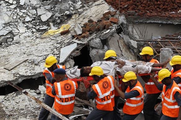 National Disaster Response Force (NDRF) workers carry an injured man rescued from the debris of a building that collapsed on the outskirts of Mumbai.