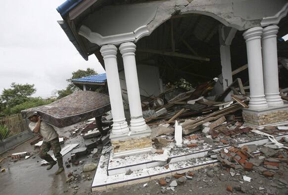Acehnese men carry a mattress they salvaged from a house destroyed by Tuesday`s earthquake in Blang Mancung, Aceh province, Indonesia.