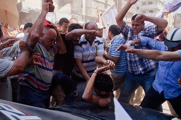 An Egyptian opposition protester is beaten by supporters of Egyptian president Mohammed Morsi, as a main raises a brick overhead, in downtown Damietta, Egypt.