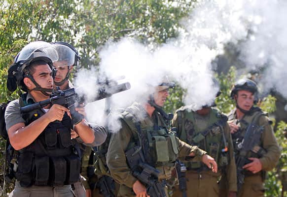 An Israeli border policeman fires a tear gas canister during a protest against an Israeli roadblock at the entrance to the West Bank village of Beitin, near Ramallah.