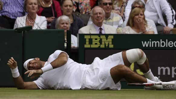 Juan Martin Del Potro of Argentina grimaces as he rolls on the ground after falling during his Men`s singles quarterfinal match against David Ferrer of Spain at the All England Lawn Tennis Championships in Wimbledon, London.