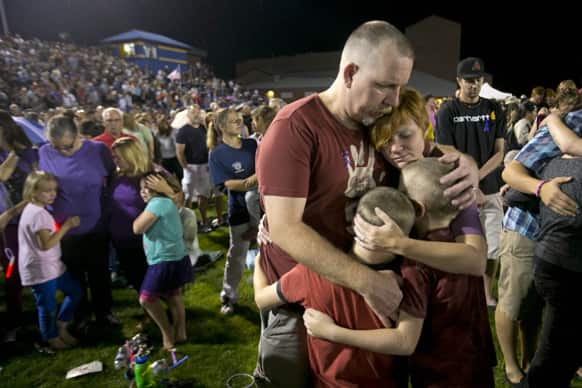 Fred Dangler and Nicole Gambill of Prescott, Ariz. embrace their children Evan, 9, right and Aidan, 8, during a candlelight vigil for the 19 firefighters killed battling the Yarnell Hill Fire, on the football field at Prescott High School in Prescott.