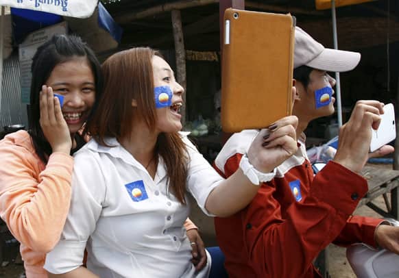 A supporter, center, of the newly merged Cambodia National Rescue Party, holds an iPad during an election campaign in Koh Kra-bey on the outskirts of Phnom Penh, Cambodia.