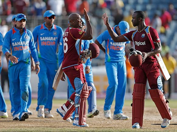 West Indies` Tino Best, front left, high fives with his batting partner Kemar Roach after they beat India by one wicket in their Tri-Nation Series cricket match in Kingston, Jamaica.