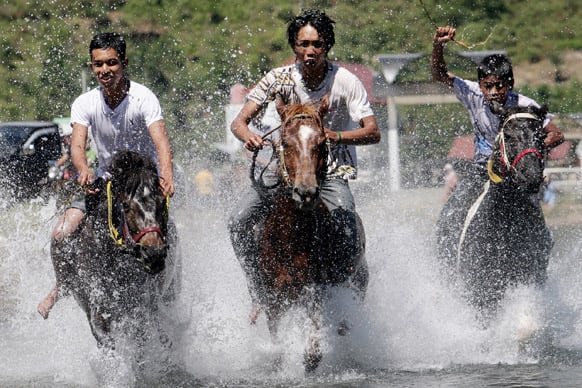 Acehnese men race their horses on the Lut Tawar Lake during a traditional horse race in Takengon, Central Aceh, Indonesia.