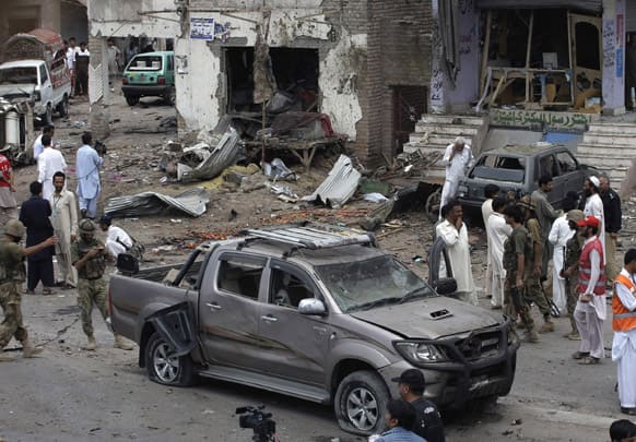 Pakistani security officials and rescue workers examine the site of car bombing on the outskirts of Peshawar, Pakistan.