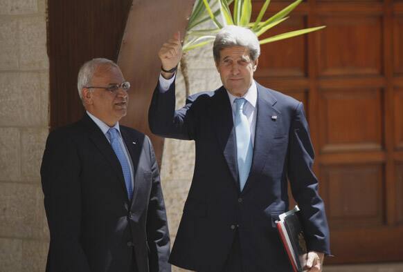 US Secretary of State John Kerry, right, and chief Palestinian negotiator Saeb Erekat wave upon his arrival for a meeting with Palestinian President Mahmoud Abbas in the West Bank city of Ramallah.