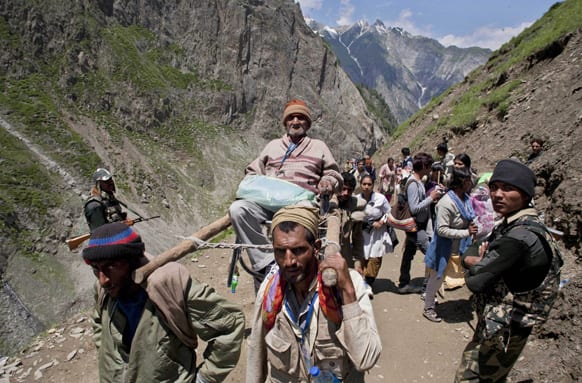 Kashmiri laborers carry a Hindu pilgrim on a trail towards Amarnath cave, near Baltal, 125 kilometers (78 miles) northeast of Srinagar.