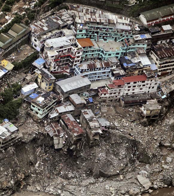 Damaged houses sit above a landslide following monsoon rains in Shrinagar. Authorities prepared Tuesday to cremate the bodies of hundreds of people who perished in monsoon flooding in northern India, as soldiers attempted to rescue tourists and pilgrims who remained stranded in a remote town.